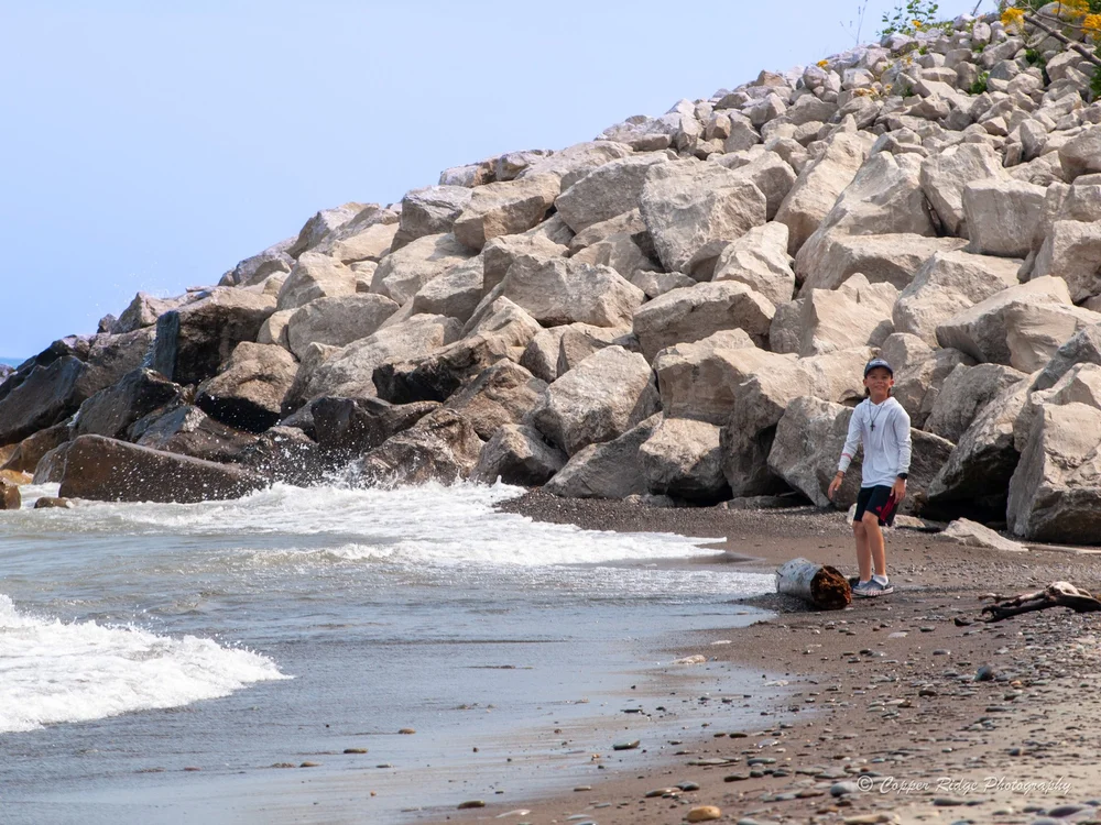 A boy exploring a rocky shoreline as waves roll in